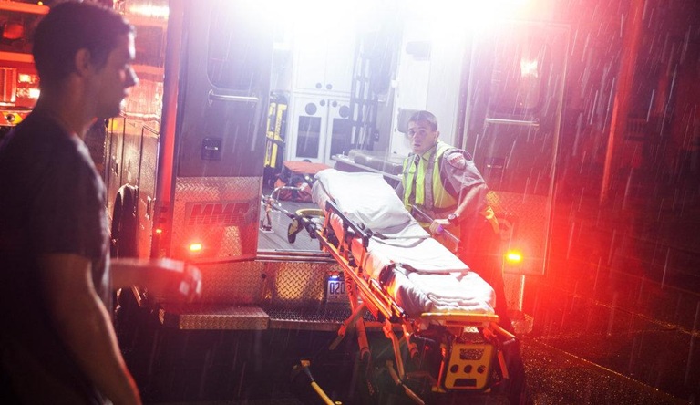 Senior Home Watch & Emergency Assist Services – Rapid response and oversight during critical times Emergency responder loading stretcher into ambulance in rain, symbolizing urgent senior care needs